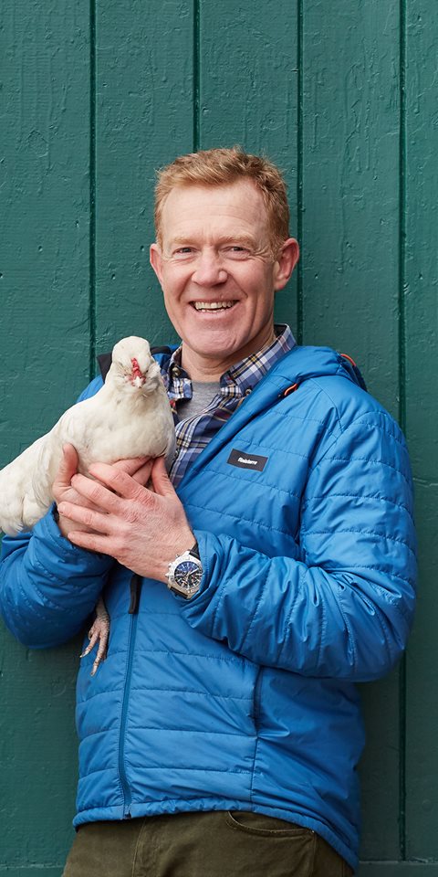 A shot of a smiling man holding a pigeon.