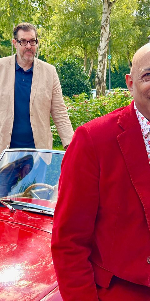 Two women and two men standing and leaning against a convertible.