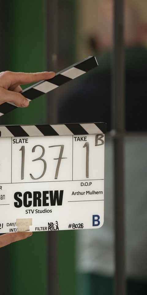 Image of a person holding a clapperboard before calling 'action'.